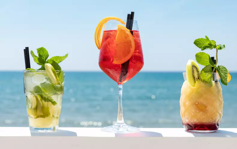 3 cocktails in primo piano con il mare sullo sfondo